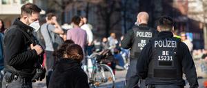 Polizisten fordern Menschen auf, eine Maske zu tragen.