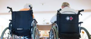 Zwei pflegebedürftige Frauen sitzen in einem Pflegeheim in ihren Rollstühlen nebeneinander.