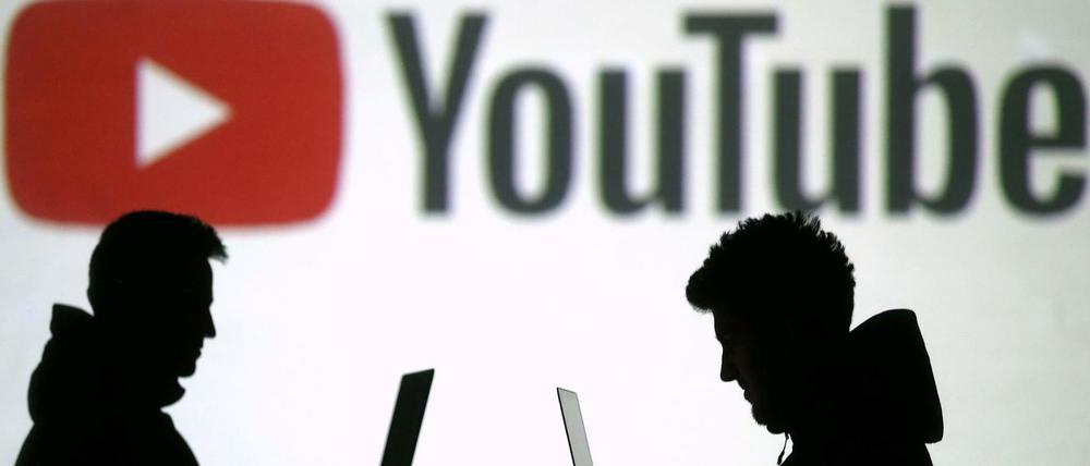 Silhouetten vor einer Projektion des Youtube-Logos.