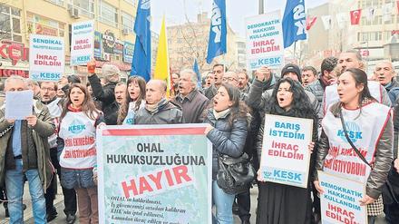 Frauen und Männer stehen mit Plakaten und Fahnen auf einem Platz in Istanbul.