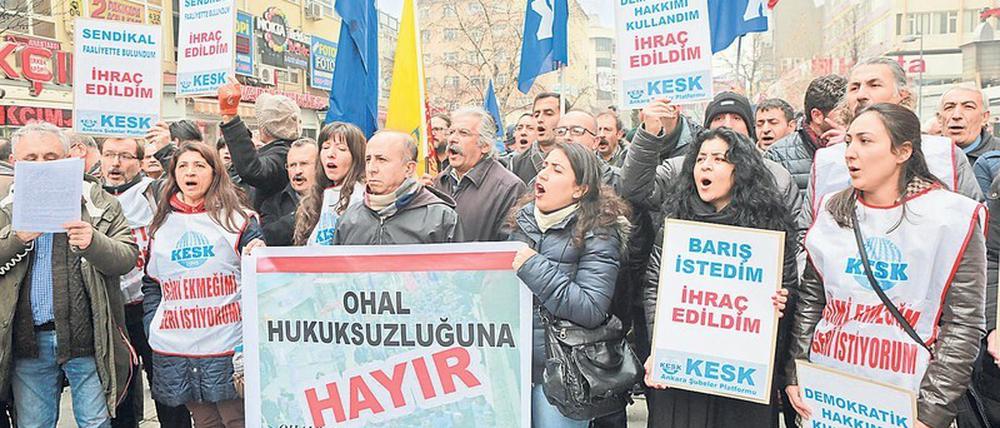 Frauen und Männer stehen mit Plakaten und Fahnen auf einem Platz in Istanbul.