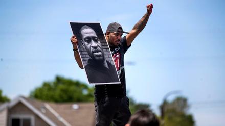 Ein Demonstrant hält ein Foto des getöteten George Floyd hoch.