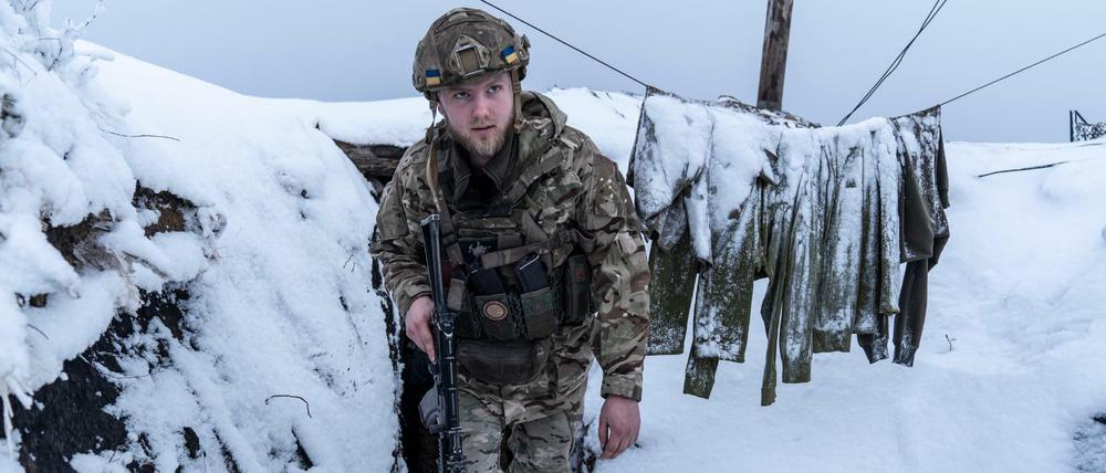 Ein ukrainischer Soldat im schneebedeckten Schützengraben an der Front in der von Russland besetzten Ostukraine.