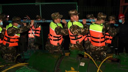 Rettungskräfte bringen Rohre in die Grube.
