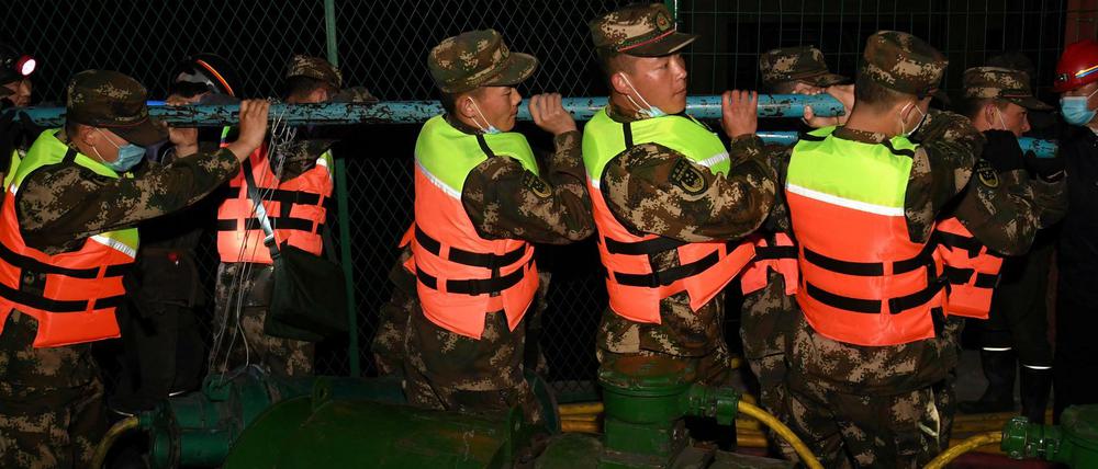 Rettungskräfte bringen Rohre in die Grube.
