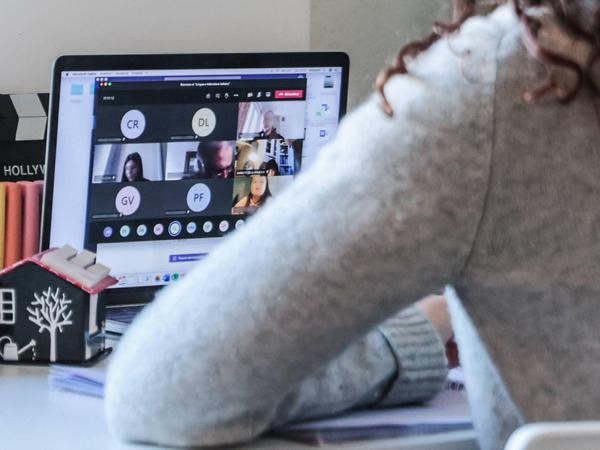 Eine junge Studentin verfolgt an ihrem Laptop eine Videokonferenz.