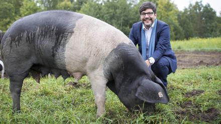 Berlins noch amtierender Justizsenator Dirk Behrendt (Grüne) neben einem Deutschen Sattelschwein in der Domäne Dahlem.