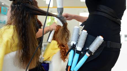 Eine Friseurin föhnt einer Kundin die Haare. Das Coronavirus hat die Branche in einen beispiellosen Krisenmodus versetzt. 