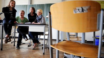 Schüler und Schülerinnen sitzen mit ihrer studentischen Nachhilfelehrerin in einem Klassenraum.