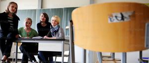 Schüler und Schülerinnen sitzen mit ihrer studentischen Nachhilfelehrerin in einem Klassenraum.
