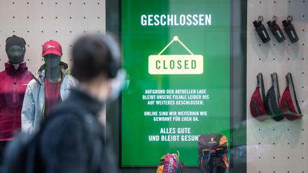 Bekleidungsgeschäft mit Hinweis auf pandemiebedingte Schließung und Onlinehandel, davor Passant mit Coronamaske.