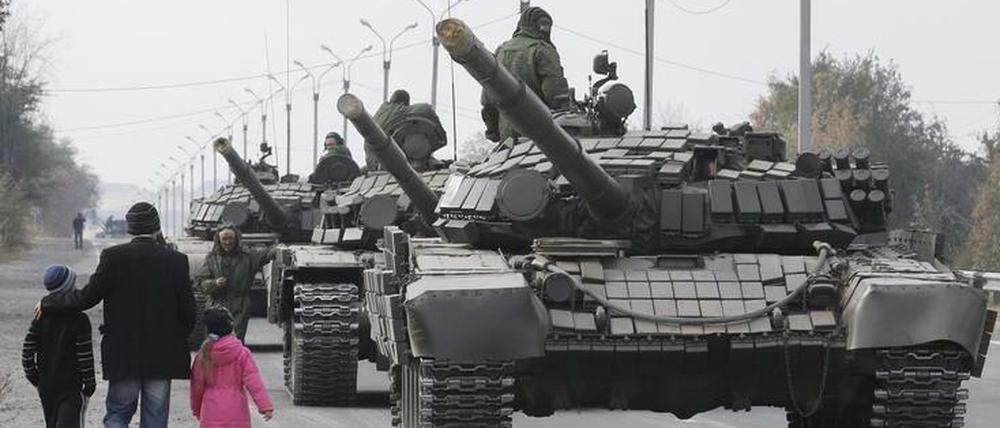Einheimische gehen am 20. Oktober 2015 in der Region Lugansk, Ukraine, an der Panzerkolonne der pro-russischen Rebellen vorbei.