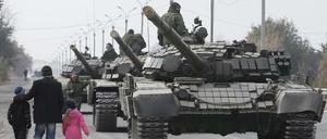 Einheimische gehen am 20. Oktober 2015 in der Region Lugansk, Ukraine, an der Panzerkolonne der pro-russischen Rebellen vorbei.