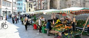 Passanten gehen in der Fußgängerzone in Tübingen an Marktständen vorbei.