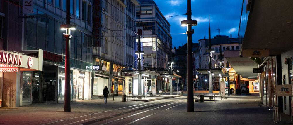 Ein Mann geht in der sogenannten blauen Stunde in Witten an den Geschäften in der ansonsten leeren Fußgängerzone vorbei. 
