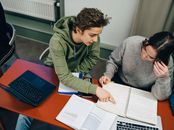 Studierende sitzen an einem Tisch und lösen ihre Aufgaben gemeinsam.