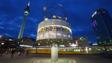 Die Weltzeituhr auf dem Alexanderplatz wird in der Abenddämmerung angestrahlt. 