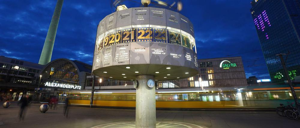 Die Weltzeituhr auf dem Alexanderplatz wird in der Abenddämmerung angestrahlt.