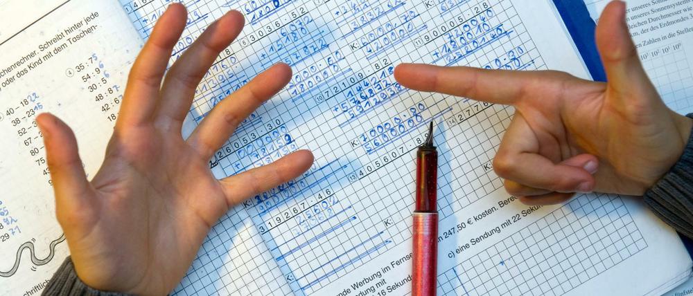 Ein Schüler rechnet Matheaufgaben mit den Fingern nach.
