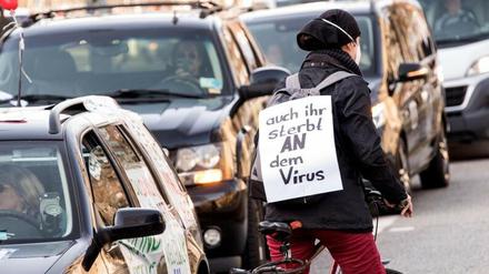 Radfahrerin protestiert mit Transparent ("Auch ihr sterbt an dem Virus") gegen Querdenker-Autokorso.