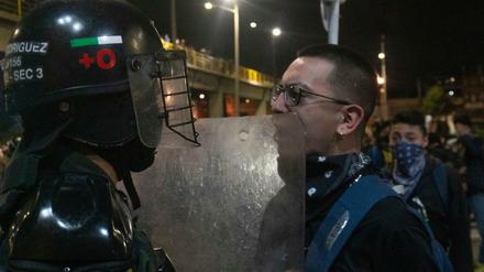 Ein Demonstrant und ein Bereitschaftspolizist stehen sich bei einem Protest gegenüber.
