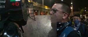 Ein Demonstrant und ein Bereitschaftspolizist stehen sich bei einem Protest gegenüber.