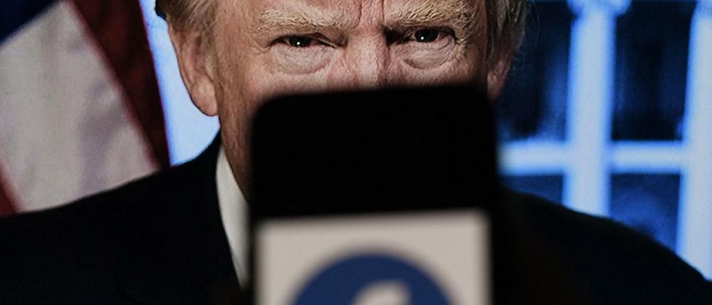 In dieser Illustration zeigt ein Telefonbildschirm ein Facebook-Logo mit dem offiziellen Porträt des ehemaligen US-Präsidenten Donald Trump im Hintergrund.