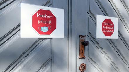 An der Eingangstür einer Schule kleben Schilder, die auf die Maskenpflicht hinweisen und auf den "Zutritt nur für Personal und Schüler".