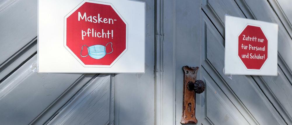 An der Eingangstür einer Schule kleben Schilder, die auf die Maskenpflicht hinweisen und auf den "Zutritt nur für Personal und Schüler".