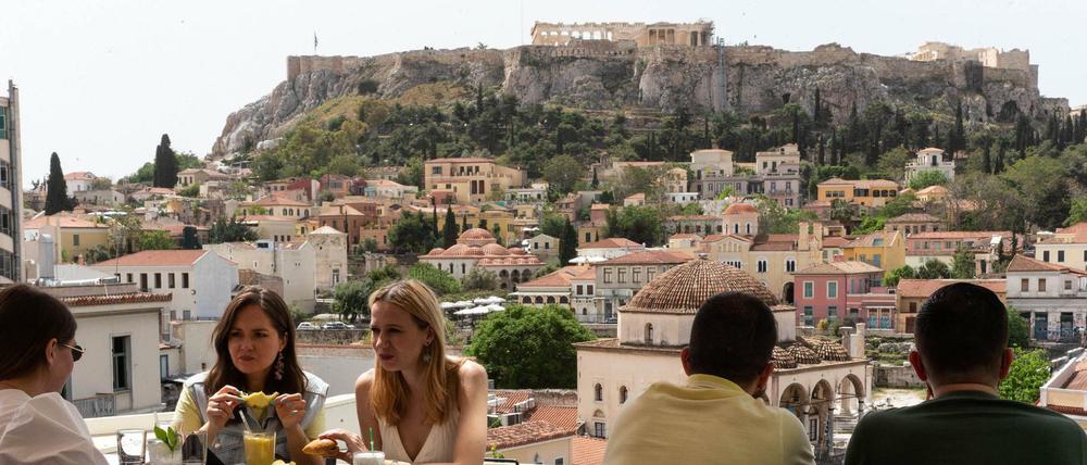 Gäste sitzen in einem Café am Fuße der Akropolis.