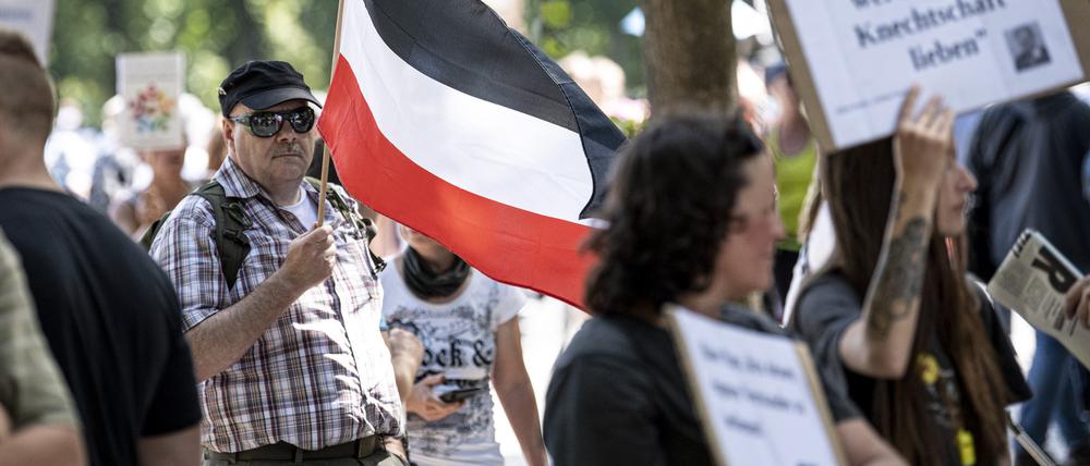 Ein Teilnehmer der Demonstration gegen die Corona-Beschränkungen trägt eine Flagge des Deutschen Reiches.