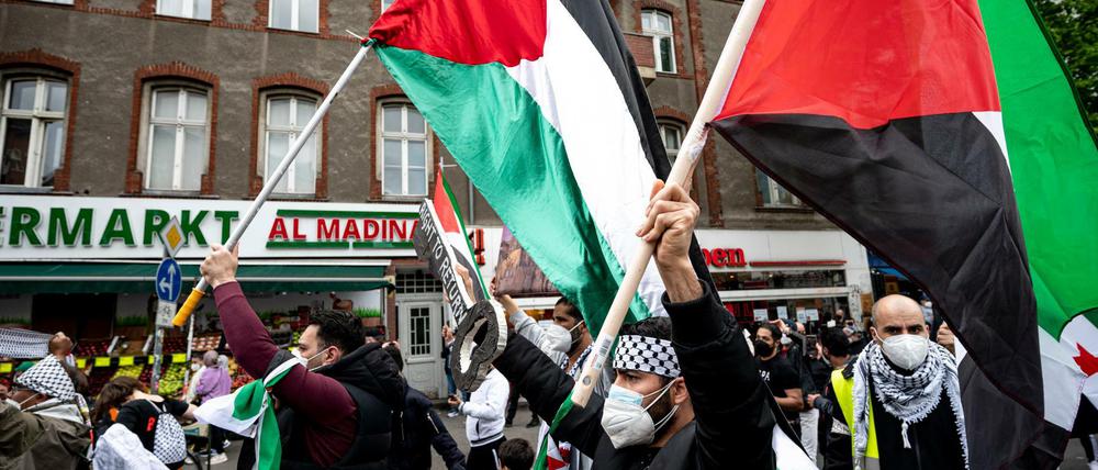 Teilnehmer der Demo verschiedener palästinensischer Gruppen laufen mit Palästina-Flaggen durch Neukölln.
