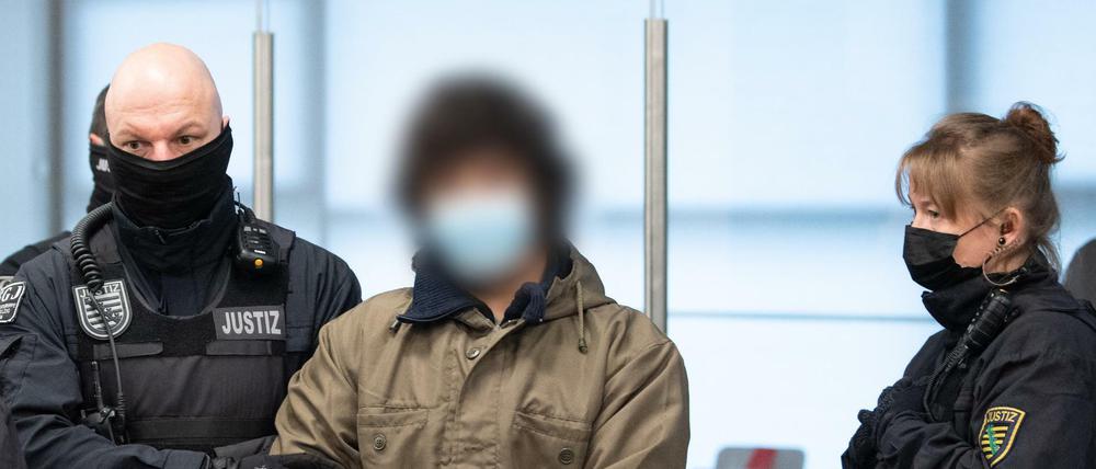 Ein Angeklagter wird vor Prozessbeginn von Justizbeamten in den Verhandlungssaal des Oberlandesgerichts (OLG) geführt. Der 21-jährigen Syrer muss sich für eine tödliche Messerattacke auf Touristen verantworten.
