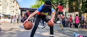 Ein Straßenkünstler dribbelt zwei Basketbälle mit verbundenen Augen vor der Bühne in der Revaler Straße.