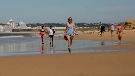 Menschen gehen am Sao-Rafael-Strand in Portugal entlang.