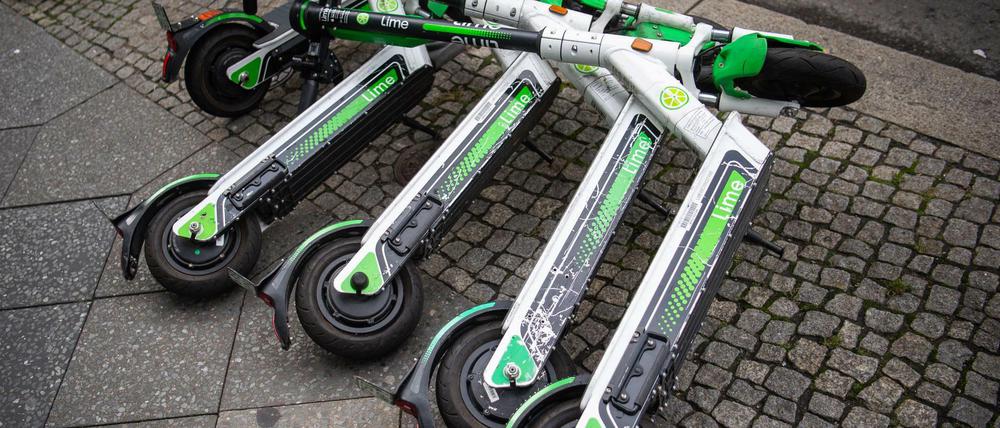 Neben- und teils übereinanderliegende E-Scooter auf einem Berliner Gehweg.