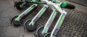 Neben- und teils übereinanderliegende E-Scooter auf einem Berliner Gehweg.