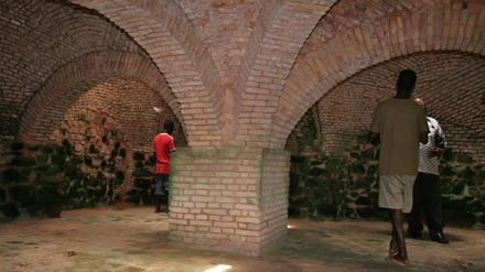 Besucher in Rückenansicht im "Slave Dungeon" im historischen Fort Groß Friedrichsburg im heutigen Ghana.