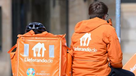 Ein Fahrradkurier des Lieferdienstes Lieferando sitzt auf dem Postplatz neben einem Rucksack.