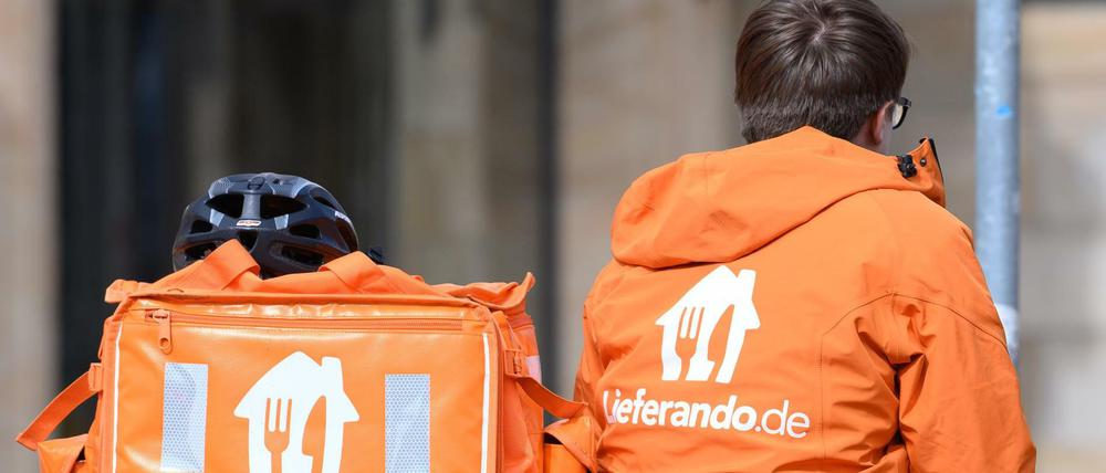 Ein Fahrradkurier des Lieferdienstes Lieferando sitzt auf dem Postplatz neben einem Rucksack.