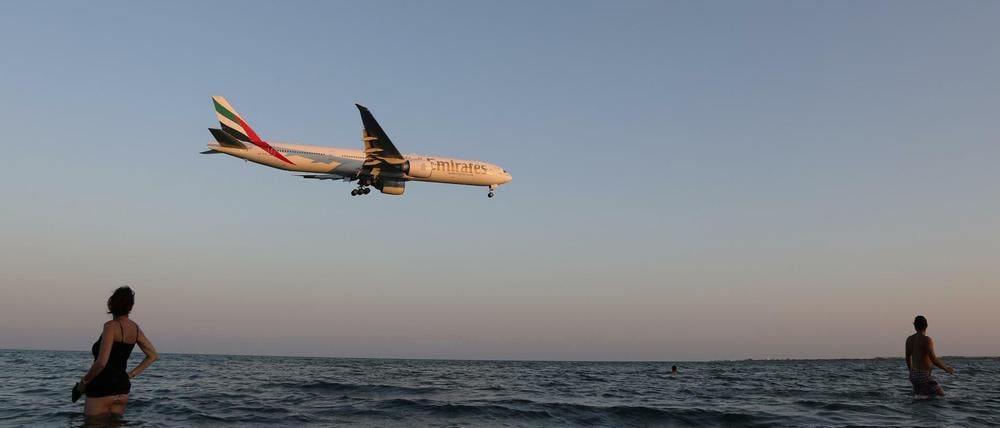 Touristen beobachten ein Boeing 777-300ER-Flugzeug von Emirates Airlines (Symbolbild)