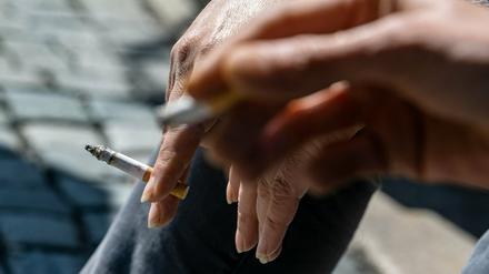 Raucher halten eine brennende Zigarette in der Hand. Der Verbrennungsprozess fördert krebserregende Stoffe zutage.