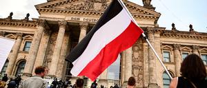 Teilnehmer einer Kundgebung gegen die Corona-Maßnahmen stehen vor dem Reichstagsgebäude - mit Reichsflagge.
