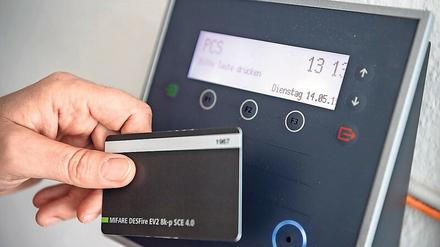 Ein Mitarbeiter erfasst seine Arbeitszeit digital an einem Terminal. In vielen Firmen ist das Alltag.