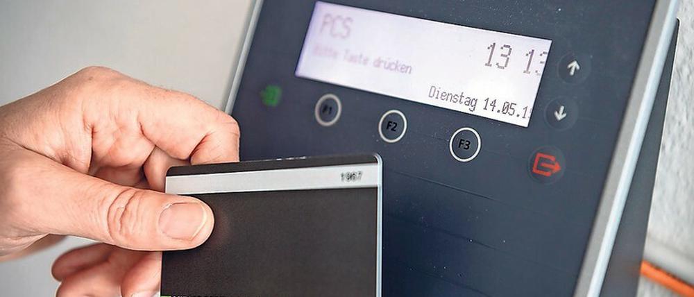 Ein Mitarbeiter erfasst seine Arbeitszeit digital an einem Terminal. In vielen Firmen ist das Alltag.