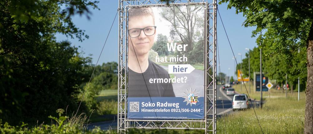 "Wer hat mich hier ermordet?" steht auf einem großen Plakat mit Foto des Opfers neben dem Tatort.