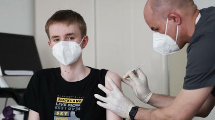 Ein Junge wird in einer Arztpraxis gegen das Coronavirus geimpft.