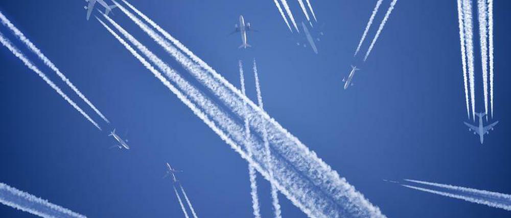 Flugzeuge mit Kondensstreifen. Das klimaschädliche am Fliegen sind nicht nur die Treibhausgasemissionen, sondern auch die Treibhauseffekte durch Kondensstreifen.