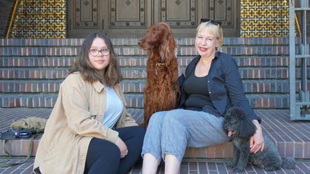 Pfarrerin Claudia Wüstenhagen und ihre Tochter Nora mit Irish Setter Grace und Zwergpudel Cherry auf den Kirchenstufen am Hohenzollernplatz in Berlin-Wilmersdorf.