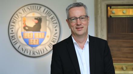 Ein Porträtbild von Günter M. Ziegler vor dem Wappen der Freien Universität.